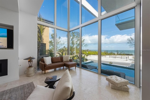 interior space featuring a water view, a fireplace, a high ceiling, and a wall of windows