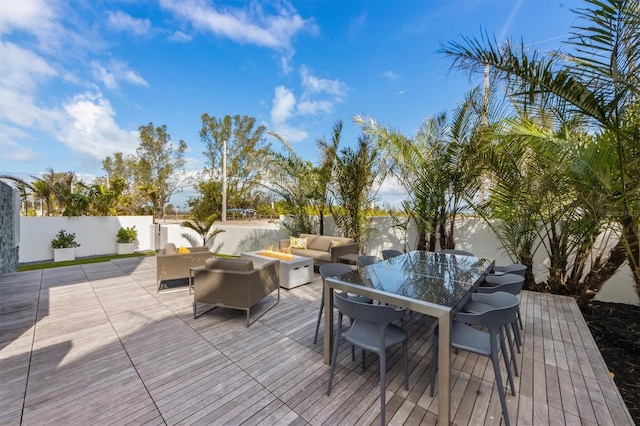 wooden terrace featuring outdoor dining space, an outdoor living space with a fire pit, and a fenced backyard