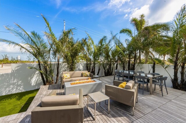 wooden terrace featuring outdoor dining area, an outdoor living space with a fire pit, and fence