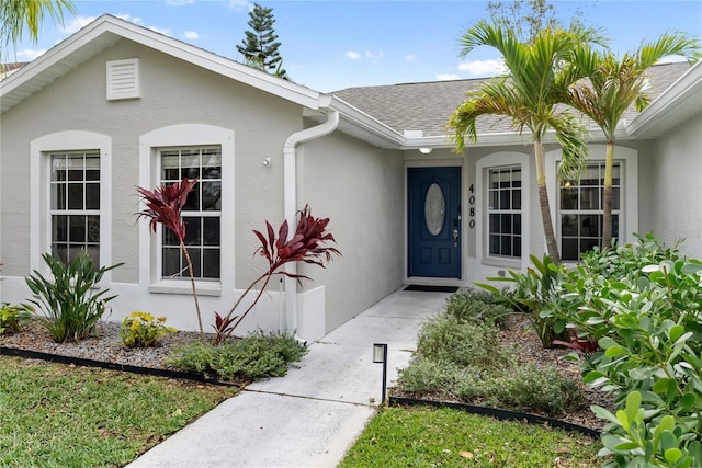 property entrance featuring roof with shingles and stucco siding