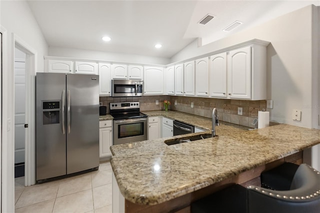 kitchen featuring visible vents, appliances with stainless steel finishes, light stone counters, a peninsula, and a sink