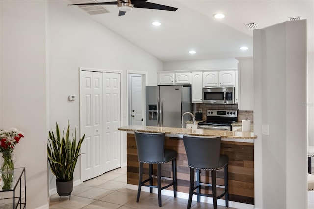 kitchen with stainless steel appliances, a peninsula, visible vents, white cabinetry, and light stone countertops