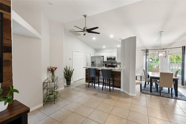 kitchen with light tile patterned floors, a breakfast bar, white cabinetry, light countertops, and appliances with stainless steel finishes