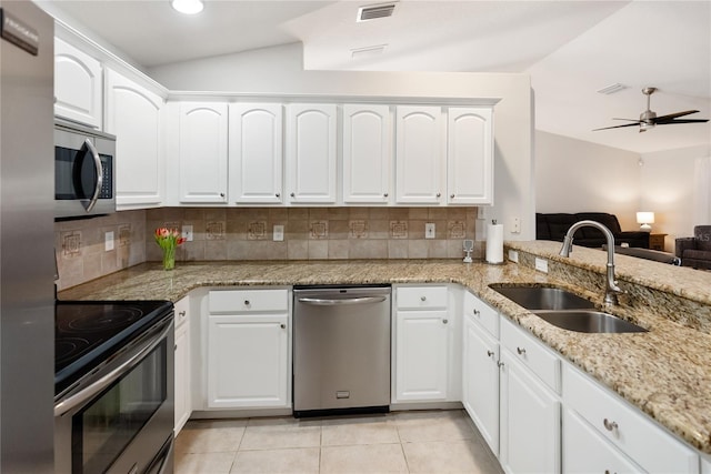 kitchen featuring stainless steel appliances, a sink, visible vents, vaulted ceiling, and backsplash