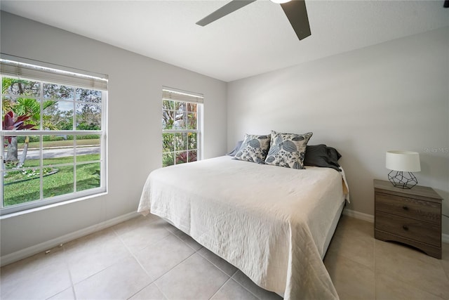 bedroom with a ceiling fan, baseboards, and light tile patterned floors