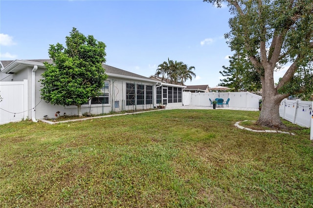 rear view of property featuring a patio area, a sunroom, a fenced backyard, and a yard