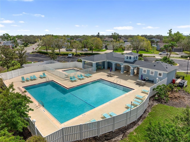 pool featuring a hot tub, a fenced backyard, a residential view, and a patio