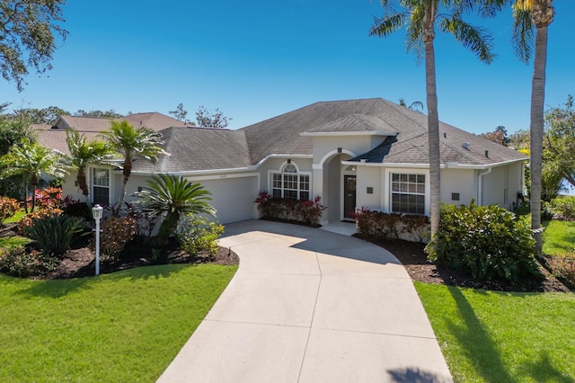 view of front of home with a garage, concrete driveway, a front lawn, and stucco siding