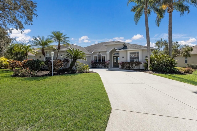 view of front of property with a garage, concrete driveway, a front lawn, and stucco siding