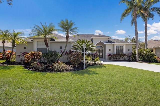 mediterranean / spanish home with french doors, a front lawn, and stucco siding