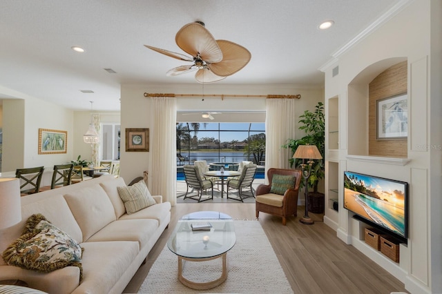 living area with light wood-style floors, recessed lighting, ornamental molding, and a ceiling fan