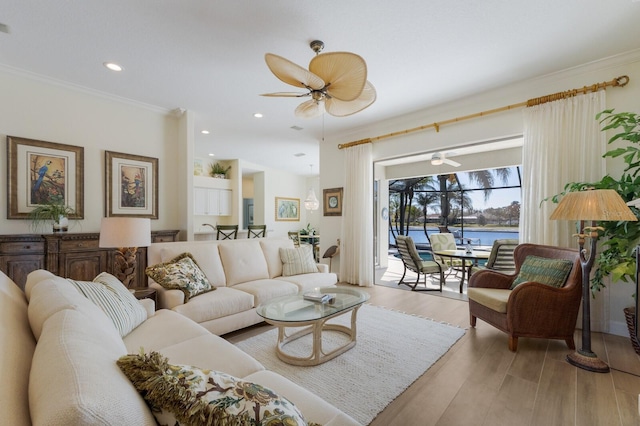 living room featuring ornamental molding, a water view, a ceiling fan, and light wood-style floors