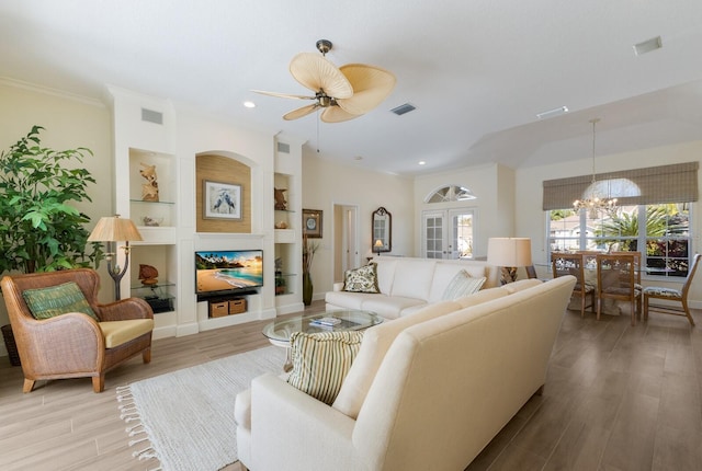 living room featuring light wood-style floors, built in shelves, visible vents, and ornamental molding