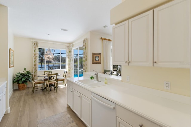 kitchen with dishwasher, decorative light fixtures, light countertops, white cabinetry, and a sink