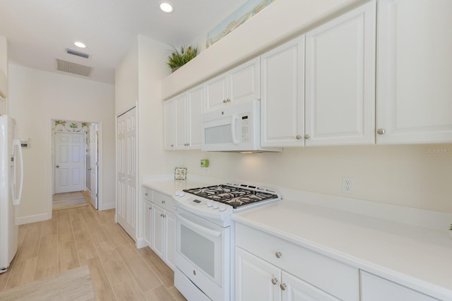 kitchen with light countertops, white appliances, visible vents, and white cabinets