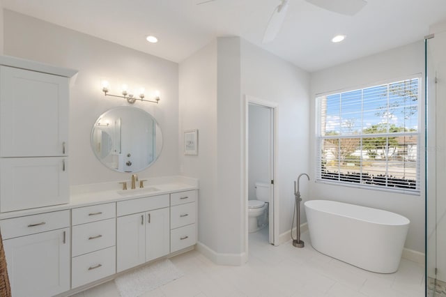 bathroom featuring recessed lighting, a soaking tub, toilet, vanity, and baseboards