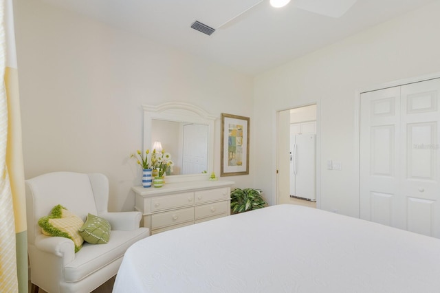 bedroom with a ceiling fan, visible vents, a closet, and freestanding refrigerator