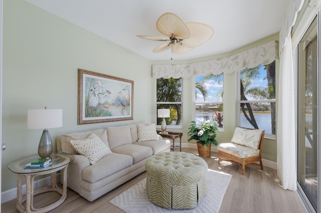 living area with light wood-style flooring, baseboards, and a ceiling fan