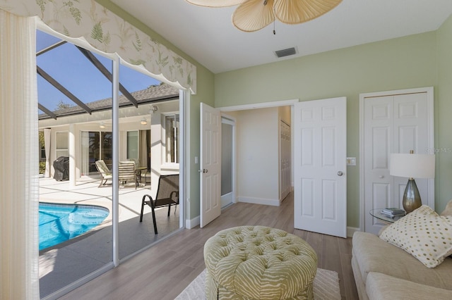 interior space featuring ceiling fan, light wood-style flooring, visible vents, a sunroom, and baseboards