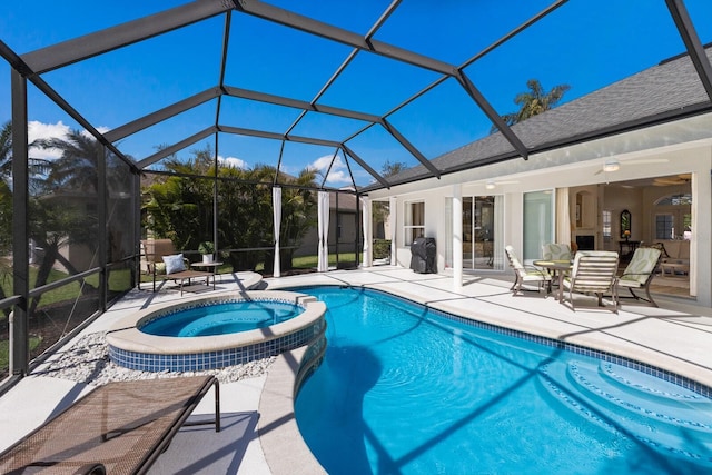 view of pool featuring glass enclosure, a pool with connected hot tub, and a patio area