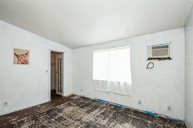 unfurnished room featuring an AC wall unit and vaulted ceiling