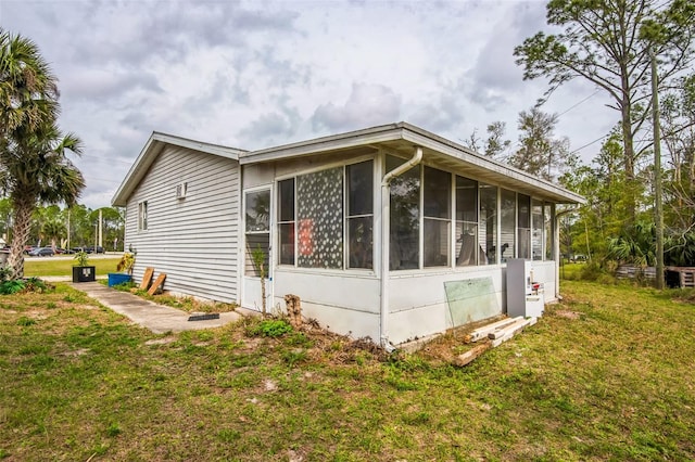 view of property exterior featuring a lawn and a sunroom