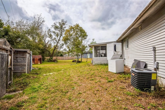 view of yard featuring an outbuilding, central AC, fence, a sunroom, and a shed