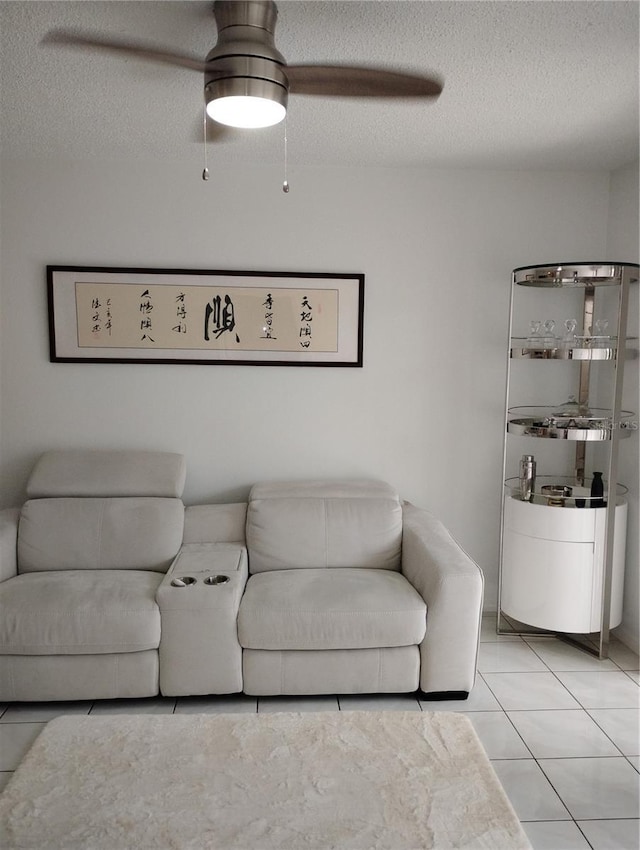 living room featuring light tile patterned flooring, ceiling fan, and a textured ceiling