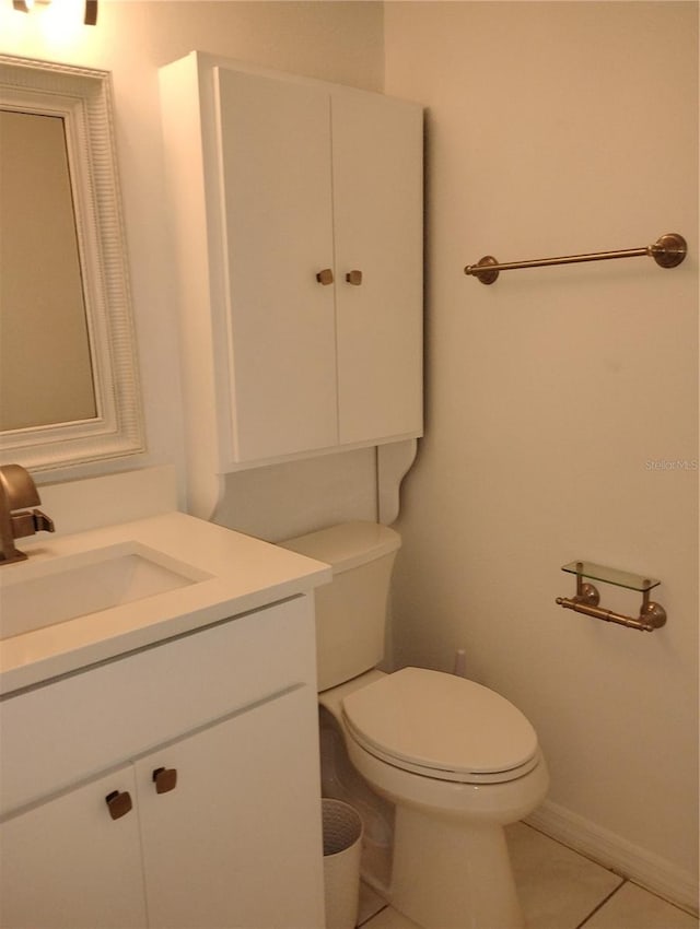 half bath featuring baseboards, vanity, toilet, and tile patterned floors