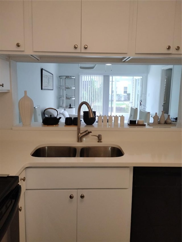 kitchen with white cabinets, range, light countertops, and a sink