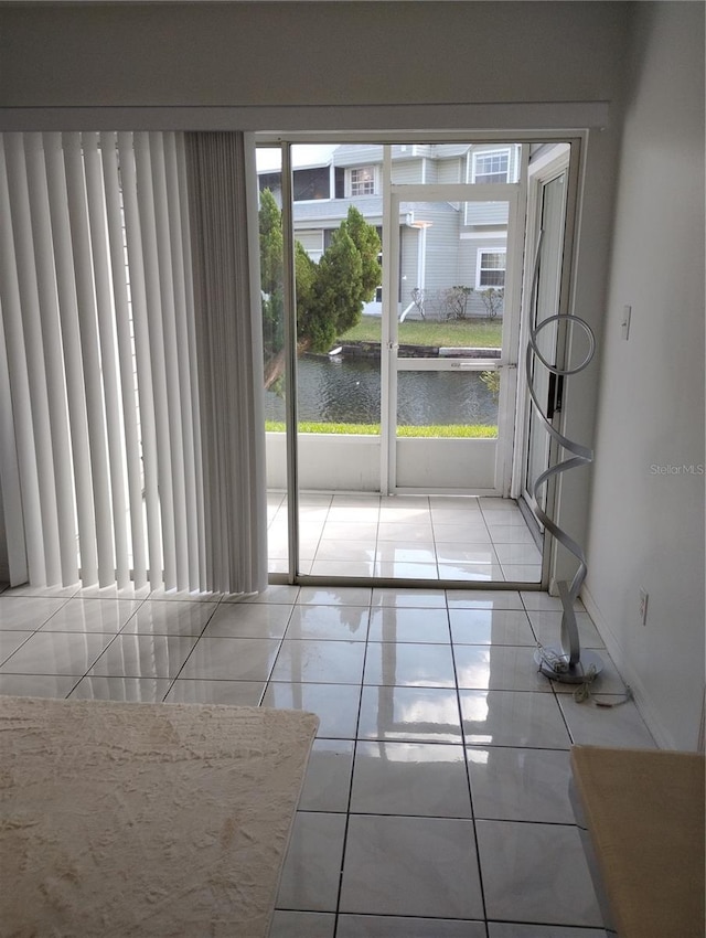 entryway with a water view, light tile patterned floors, and baseboards