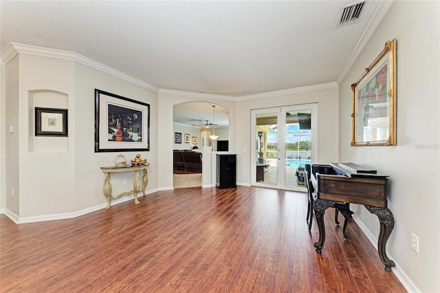 living area featuring arched walkways, wood finished floors, visible vents, ornamental molding, and french doors