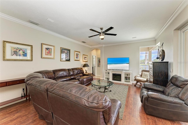 living room featuring a fireplace, arched walkways, wood finished floors, and ornamental molding