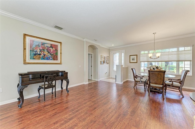 dining space with arched walkways, wood finished floors, visible vents, baseboards, and crown molding