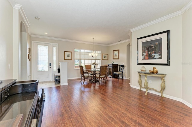 dining area featuring baseboards, ornamental molding, a chandelier, and wood finished floors