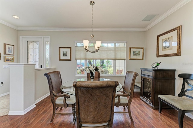 dining room with baseboards, visible vents, wood finished floors, an inviting chandelier, and crown molding