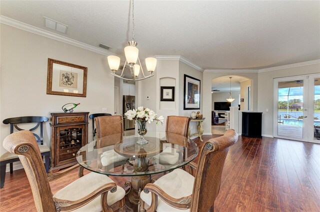 dining room with visible vents, arched walkways, hardwood / wood-style floors, and a chandelier