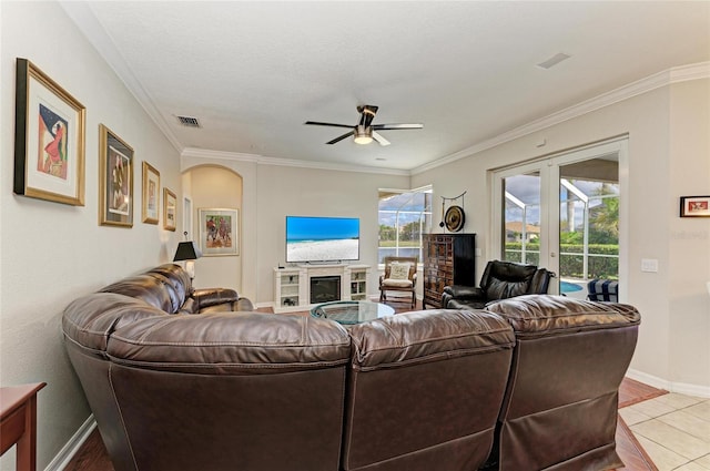 living area featuring arched walkways, a fireplace, visible vents, french doors, and ornamental molding