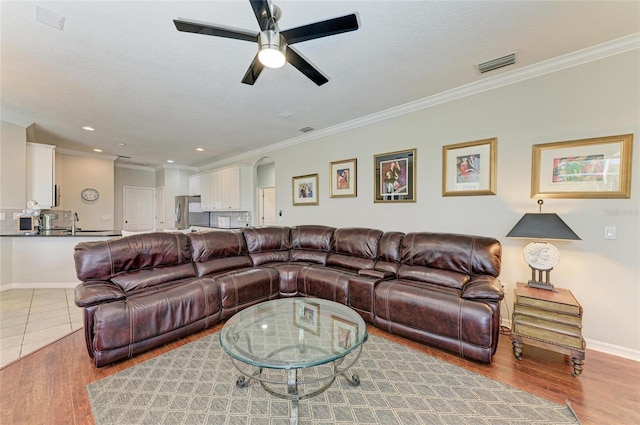 living room featuring light wood-style floors, visible vents, and ornamental molding