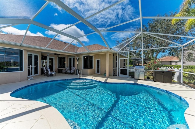 pool with glass enclosure, a ceiling fan, and a patio