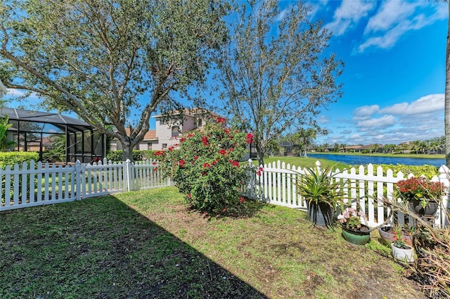 view of yard with glass enclosure, a water view, and fence