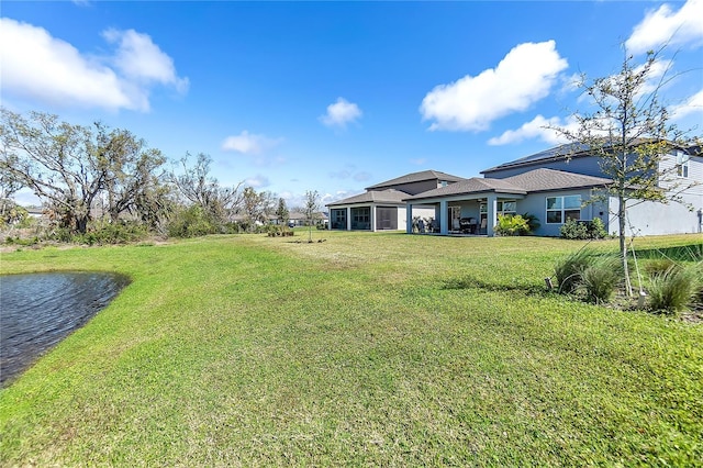 view of yard with a sunroom and a water view