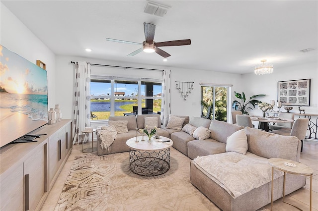 living room featuring recessed lighting, visible vents, a water view, and ceiling fan with notable chandelier