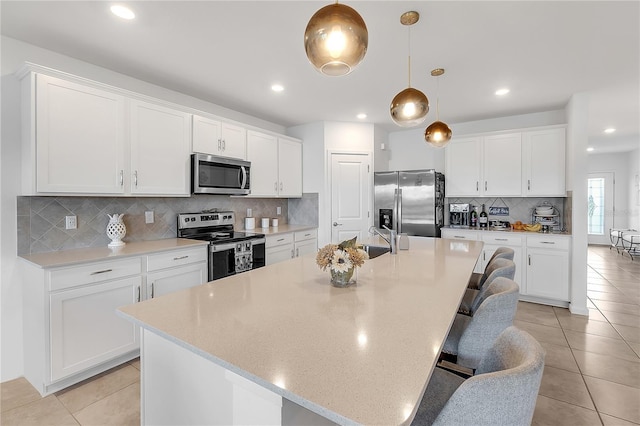 kitchen featuring a kitchen island with sink, appliances with stainless steel finishes, and white cabinetry