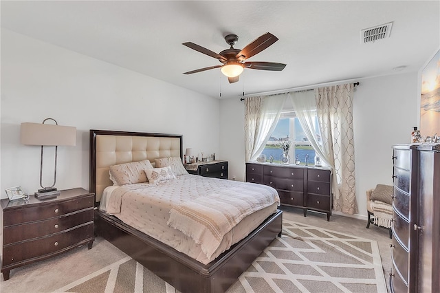 bedroom with ceiling fan, visible vents, and light colored carpet