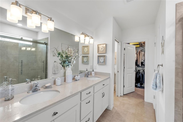 bathroom featuring a spacious closet, double vanity, a stall shower, and a sink