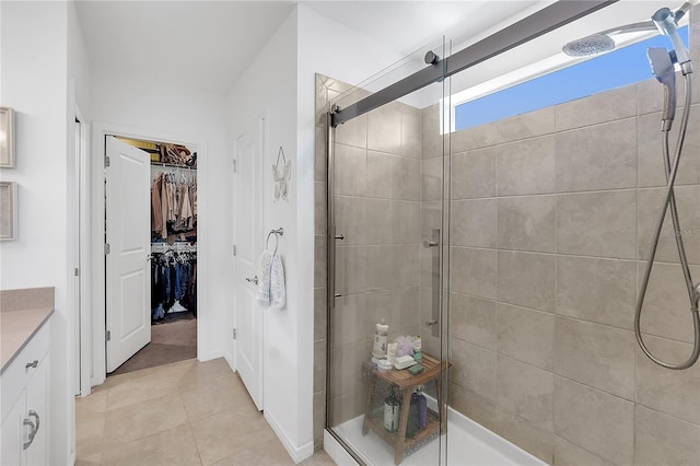 bathroom featuring a stall shower, tile patterned flooring, vanity, and a walk in closet