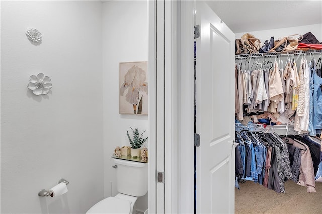 bathroom featuring a spacious closet and toilet