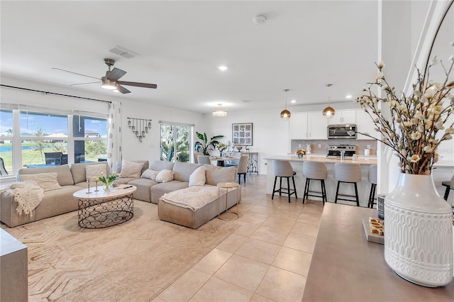 living area featuring light tile patterned floors, a ceiling fan, visible vents, and recessed lighting