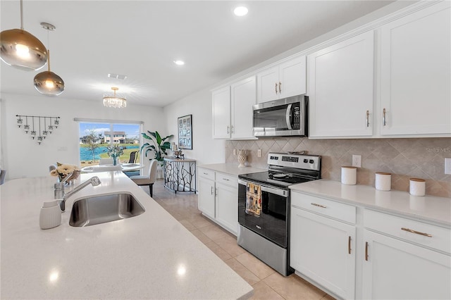 kitchen with light tile patterned floors, white cabinets, decorative backsplash, appliances with stainless steel finishes, and a sink